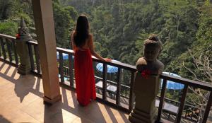 una mujer en un vestido rojo de pie en un balcón en Villa Kalisat Resort, en Ubud