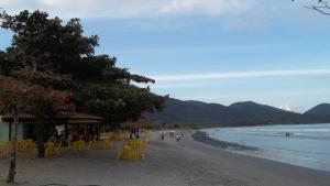 a beach with yellow chairs and people on the beach at Ubatuba Apartamento Maurilio in Ubatuba