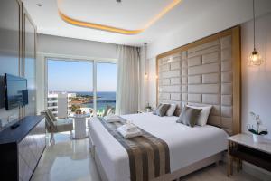 a bedroom with a large bed and a large window at Constantinos the Great Beach Hotel in Protaras