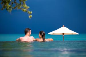 un hombre y una mujer en el agua junto a un paraguas en Sea Dance Resort, en Choeng Mon Beach
