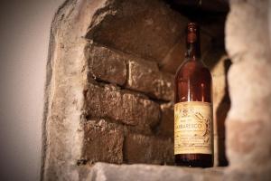 Una botella de vino sentada junto a una pared de piedra. en Villa Vinory - Tenuta il Sogno, en San Marzano Oliveto