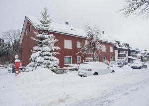 a snow covered yard in front of a red house at Wohlfühloase am Bikepark und Skigebiet, 2 Schlafzimmer, abschließbarer Fahrradkeller in Winterberg