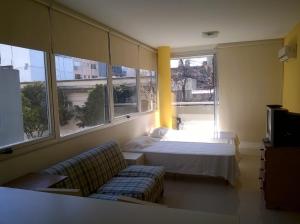Cette chambre comprend un lit, un canapé et des fenêtres. dans l'établissement SOLAR DEL ABASTO, à Buenos Aires