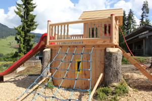 un parque infantil con un tobogán y un árbol en Pension Luzenberg en Auffach