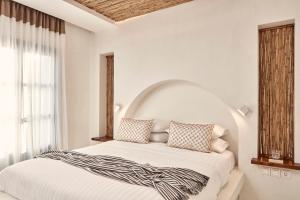 a white bedroom with a bed with a large window at Parian Boutique Hotel in Naousa