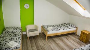 1 dormitorio con 2 camas, silla y reloj en Penzion U Ďáblova kopyta, en Rakvice