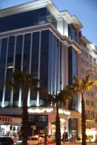 een groot gebouw met palmbomen ervoor bij Emir Royal Hotel in Adana