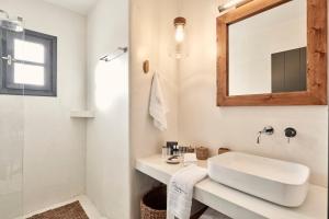 a white bathroom with a sink and a mirror at Parian Boutique Hotel in Naousa