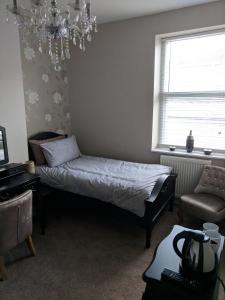 a bedroom with a bed and a chair and a chandelier at Lion House Bed & Breakfast with Restaurant in Combe Martin
