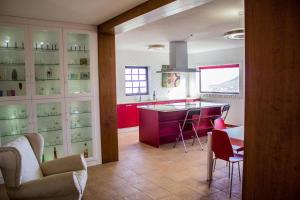 een keuken met rode kasten en een bar met stoelen bij Quiet Rural House Ten Minutes From The Beach in Puerto del Rosario