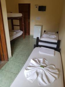 a room with three beds with towels on them at POUSADA DO GALEGO in Itaguaí