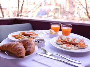 einen Tisch mit 2 Tellern Frühstücksprodukte und Getränke in der Unterkunft Oda Hotel Tirana in Tirana