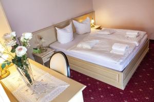 una habitación de hotel con una cama y una mesa con flores en Penzion Rosenthal en Ružindol