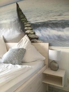 a bedroom with a bed and a painting of the ocean at Kleine Sonne in Grömitz