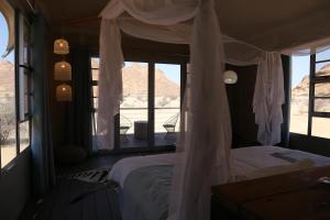 a bedroom with a canopy bed with a view at Spitzkoppen Lodge in Usakos