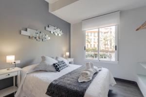 Habitación blanca con cama y ventana en La Casa de los Espejos, en Alicante