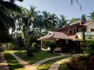 a house with a garden and a driveway at Maleyam Homestay Riverside in Kozhikode