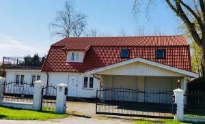 Casa blanca con techo rojo y valla en Gästhus La Casa en Sölvesborg