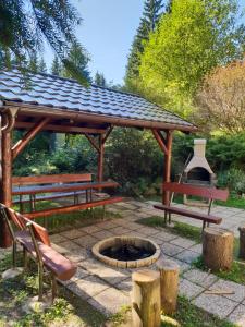 a picnic shelter with benches and a fire pit at Squirrel cottage in Dolná Lehota
