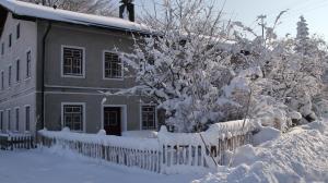 una casa cubierta de nieve con un árbol y una valla en Alte Wirtschaft, en Hohenlinden