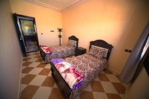 a bedroom with two beds and a checkered floor at Résidence dikre in Ouarzazate