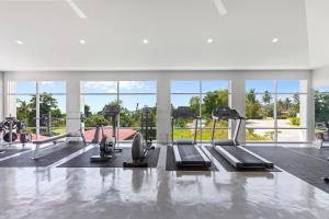 a gym with several treadmills and machines and windows at Villa Cannes with gym and tennis court in Choeng Mon Beach