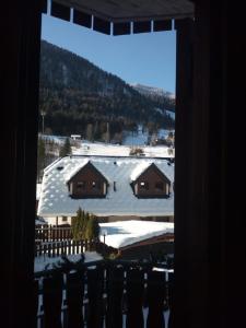 a view of a snow covered house from a window at Casa vacanze Rododendro in Tarvisio