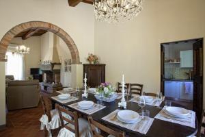 uma sala de jantar com uma mesa com cadeiras e um lustre em Villa Il Sole em Cortona