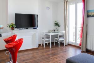 - un salon avec une télévision, une table et des chaises dans l'établissement Les quais du Port, à Marseille