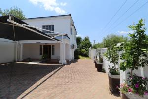 a white building with potted plants on a brick sidewalk at Sentosa Guest House in Francistown