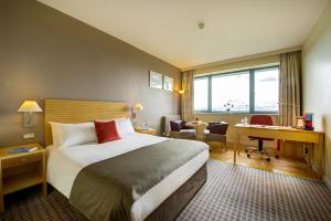 um quarto de hotel com uma cama grande e uma secretária. em Cork Airport Hotel em Cork