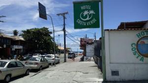 a street with parked cars and a sign for a hotel at Hotel Costa Verde in Porto Seguro