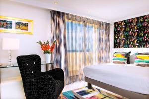 a bedroom with a bed and a black chair at Hôtel West End Promenade in Nice