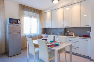 - une cuisine avec des placards blancs, une table et des chaises dans l'établissement La Casa del Giardin Grande, à Udine