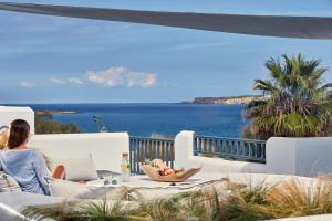 a woman sitting on a couch looking out at the ocean at Parian Boutique Hotel in Naousa