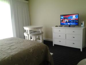 1 dormitorio con 1 cama y vestidor con TV en Surf & Sand Beach Motel en South Yarmouth