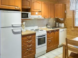 a kitchen with wooden cabinets and white appliances at Holiday Home Levimaa by Interhome in Sirkka