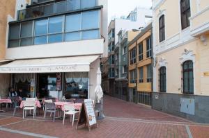 una strada vuota con tavoli e sedie di fronte a un negozio di Room in My Vintage Home a Las Palmas de Gran Canaria