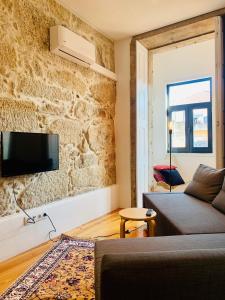 a living room with a couch and a tv on a stone wall at Oporto Chic&Cozy - Santo Ildefonso in Porto