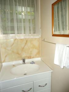 een witte badkamer met een wastafel en een raam bij Park Lodge Motel in Te Awamutu