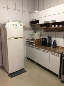 uma cozinha com um frigorífico branco num quarto em casa em Martins de Sá em Caraguatatuba