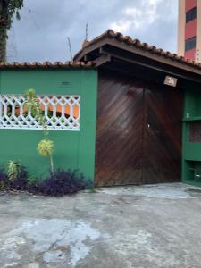 a green garage with a large wooden door at casa em Martins de Sá in Caraguatatuba