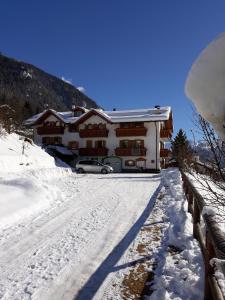 dom na śniegu z samochodem zaparkowanym na podjeździe w obiekcie Casa Bamby w mieście Cogolo