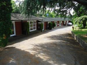 a row of red buildings with a driveway at Park Lodge Motel in Te Awamutu