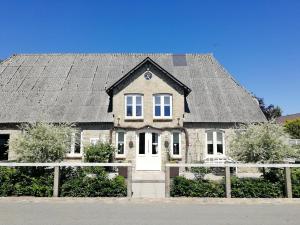 ein Haus mit einem grauen Dach auf einer Straße in der Unterkunft Haus Friedrichsen in Hollingstedt