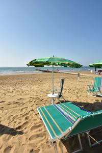 two lounge chairs and an umbrella on a beach at Residence Mariavittoria in Lido di Jesolo
