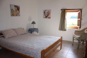 une chambre avec un lit, une fenêtre et une chaise dans l'établissement Gîtes Grand Pré ! et la Roulotte de Roquecor, à Roquecor 122 autres photos