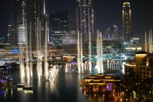 a group of water fountains in a city at night at Burj Grand Apartment - Four Bedrooms in Dubai