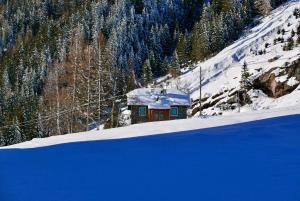 une petite maison dans la neige sur une montagne dans l'établissement Il Cortese, à Chiareggio