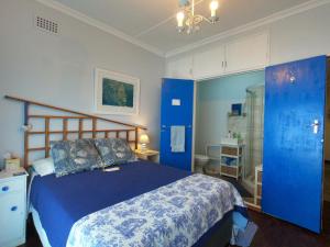 a blue bedroom with a bed and a bathroom at Leo's Den in Fish hoek